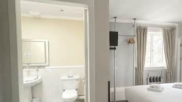 A hotel room with a bathroom, a bed, and a window with curtains.