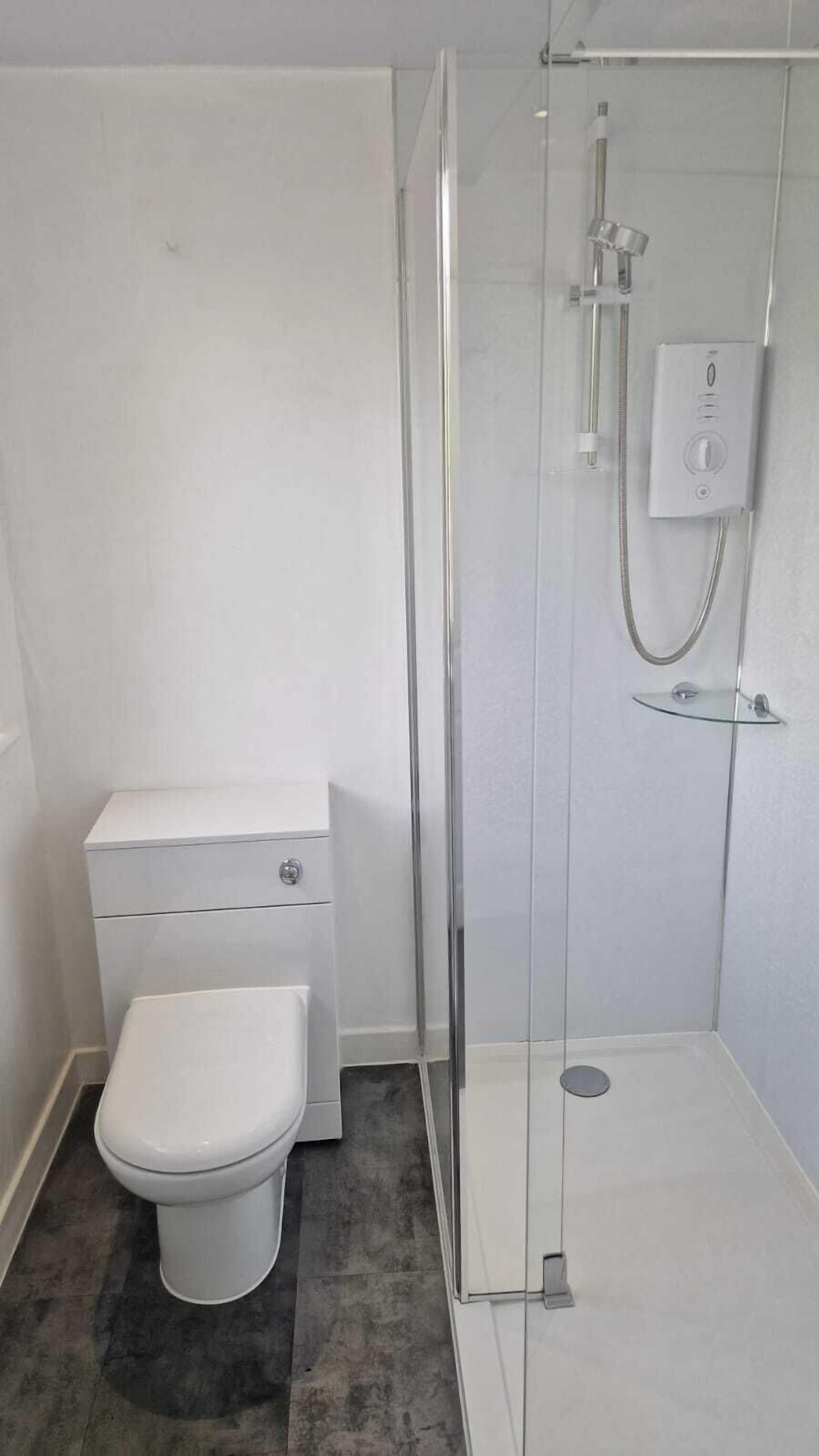A bathroom with a toilet, a glass-enclosed shower, and a white sink.
