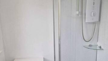 A bathroom with a toilet, a glass-enclosed shower, and a white sink.