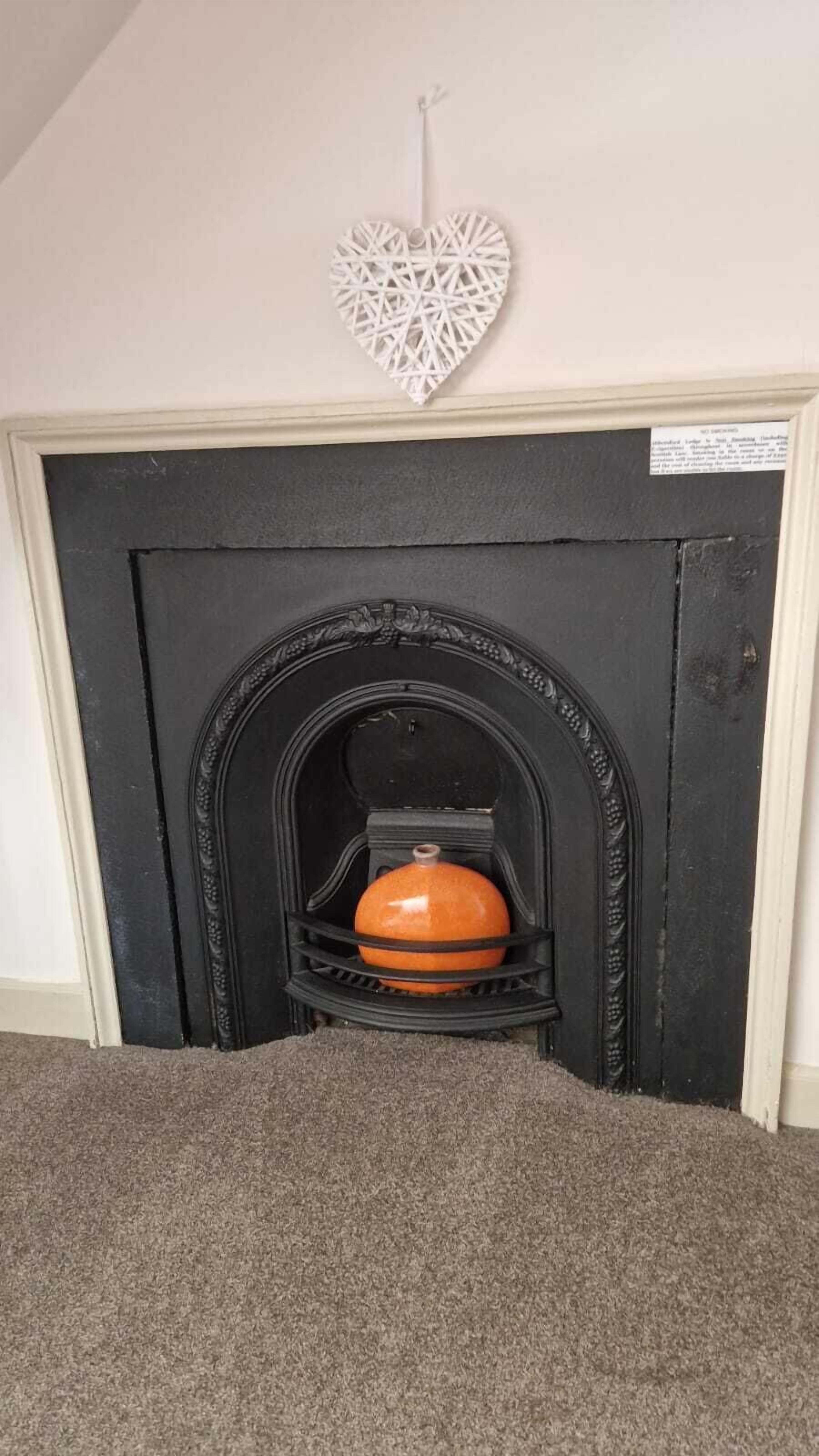 A fireplace with a decorative heart hanging above it.