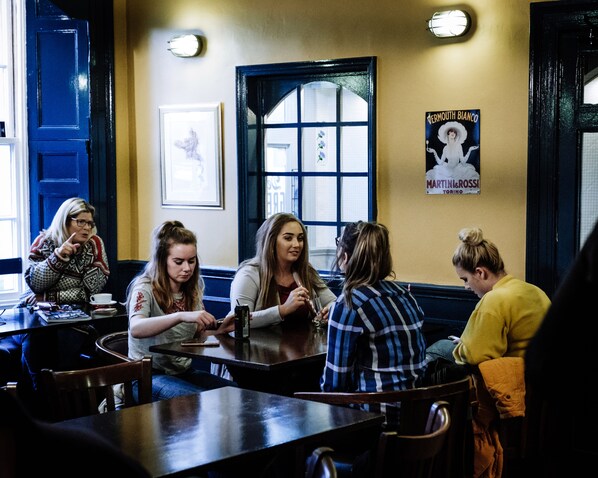 A group of people seated at a table in a restaurant with a poster on the wall and a window with a view.