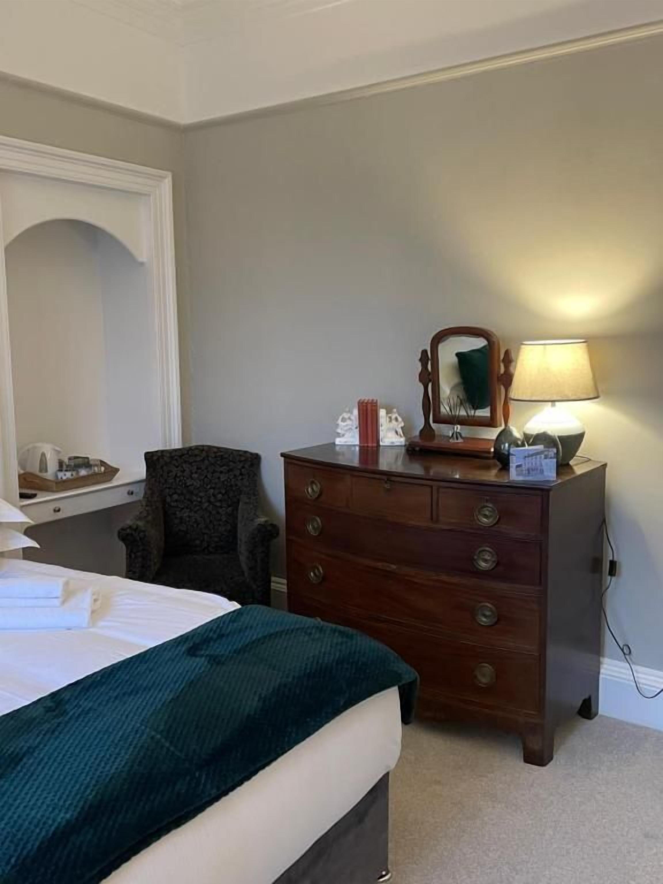 Ein Hotelzimmer mit Bett, Schminktisch, Stuhl und Lampe.