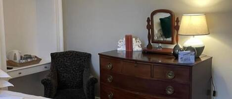 Ein Hotelzimmer mit Bett, Schminktisch, Stuhl und Lampe.