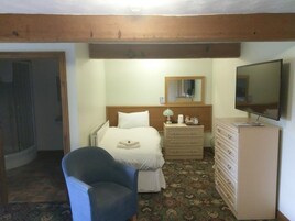 Una habitación de hotel con cama, una silla, cómoda, espejo y televisor.