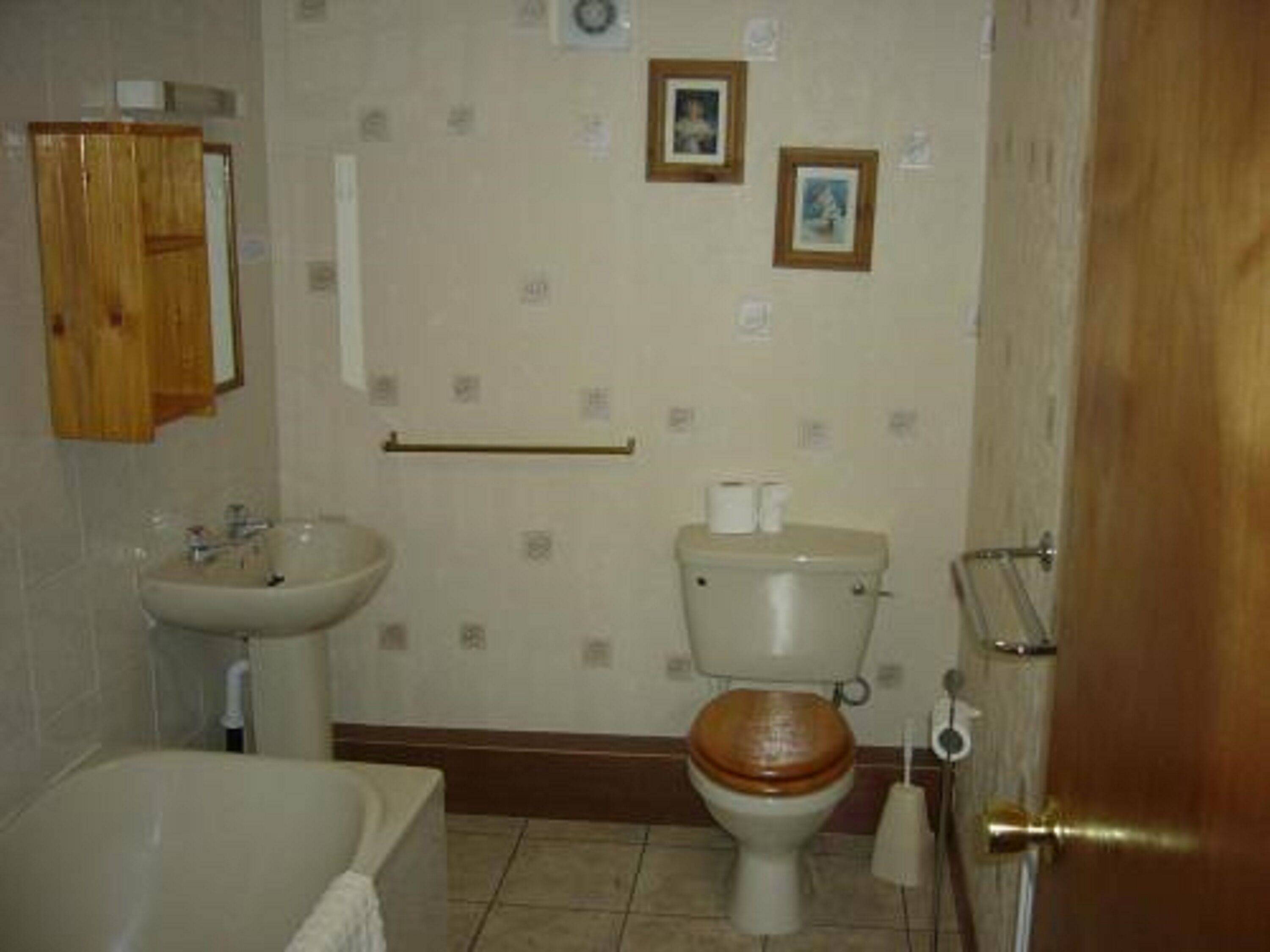 A bathroom with a bathtub, sink, toilet, and wooden door.