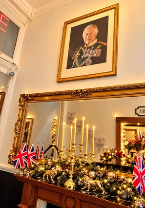 A decorated mantelpiece with a framed portrait, candles, and British flags. - Jubilee Hotel Victoria (London)