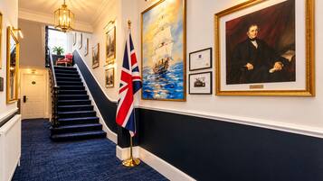 A hallway with a staircase, framed artwork, and flags.