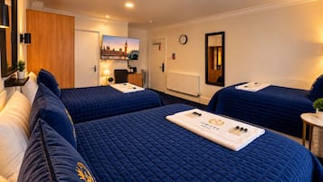 A hotel room with two beds, a desk, a chair, a clock, and a painting of a cityscape.