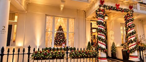 Un bâtiment doté d’une entrée imposante, d’un sapin de Noël et de décorations festives.