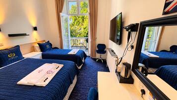 A hotel room with two beds, a desk, a chair, a television, and a window with curtains.