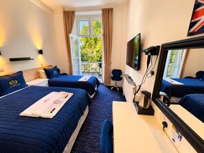 Camera d'albergo con due letti, una scrivania, una sedia, una televisione e una finestra con tende.