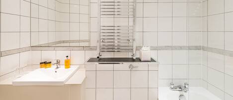 Ein modernes Badezimmer mit einem weißen Waschbecken, einer Badewanne und einem Handtuchhalter.