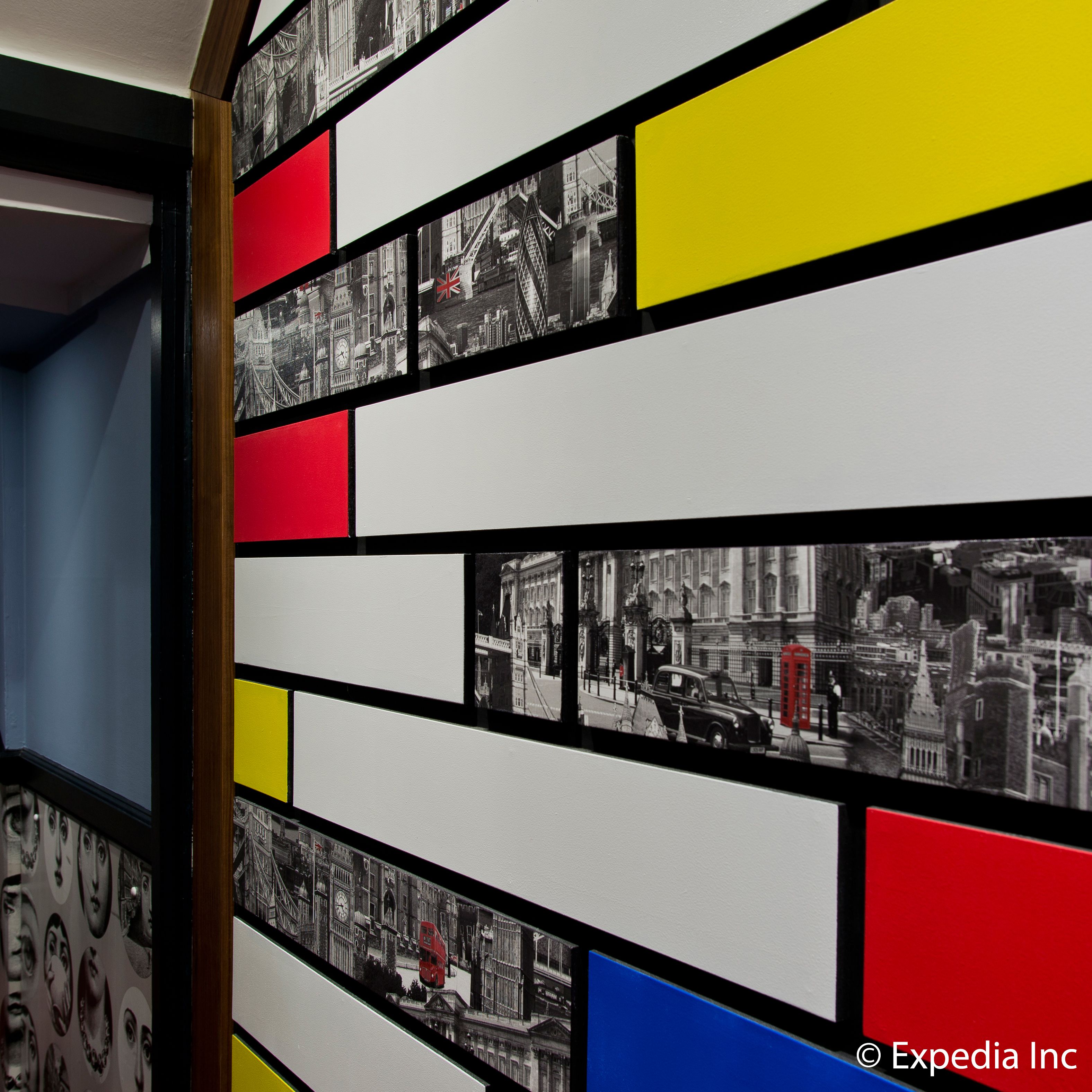 A wall with black and white photographs of cityscapes, framed in black, with red, yellow, and blue panels.