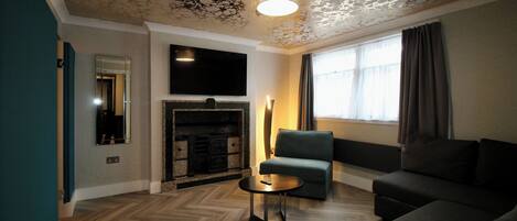 A modern living room with a fireplace, a flat-screen TV, a sofa, and a coffee table.