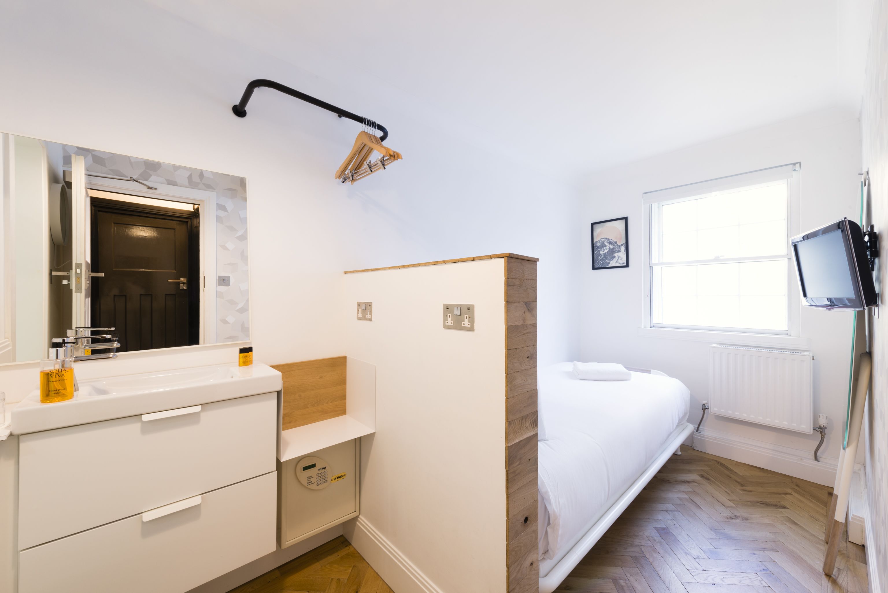 A modern bathroom with a white sink, mirror, and wooden vanity.