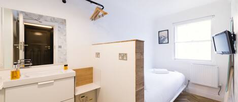 A modern bathroom with a white sink, mirror, and wooden vanity.