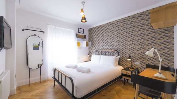 Une chambre à coucher moderne avec un lit, une table de chevet, un bureau et une chaise.