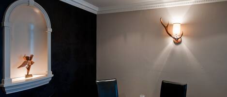 Un comedor con una mesa redonda dispuesta para cuatro, una lámpara de pared y un adorno mural.