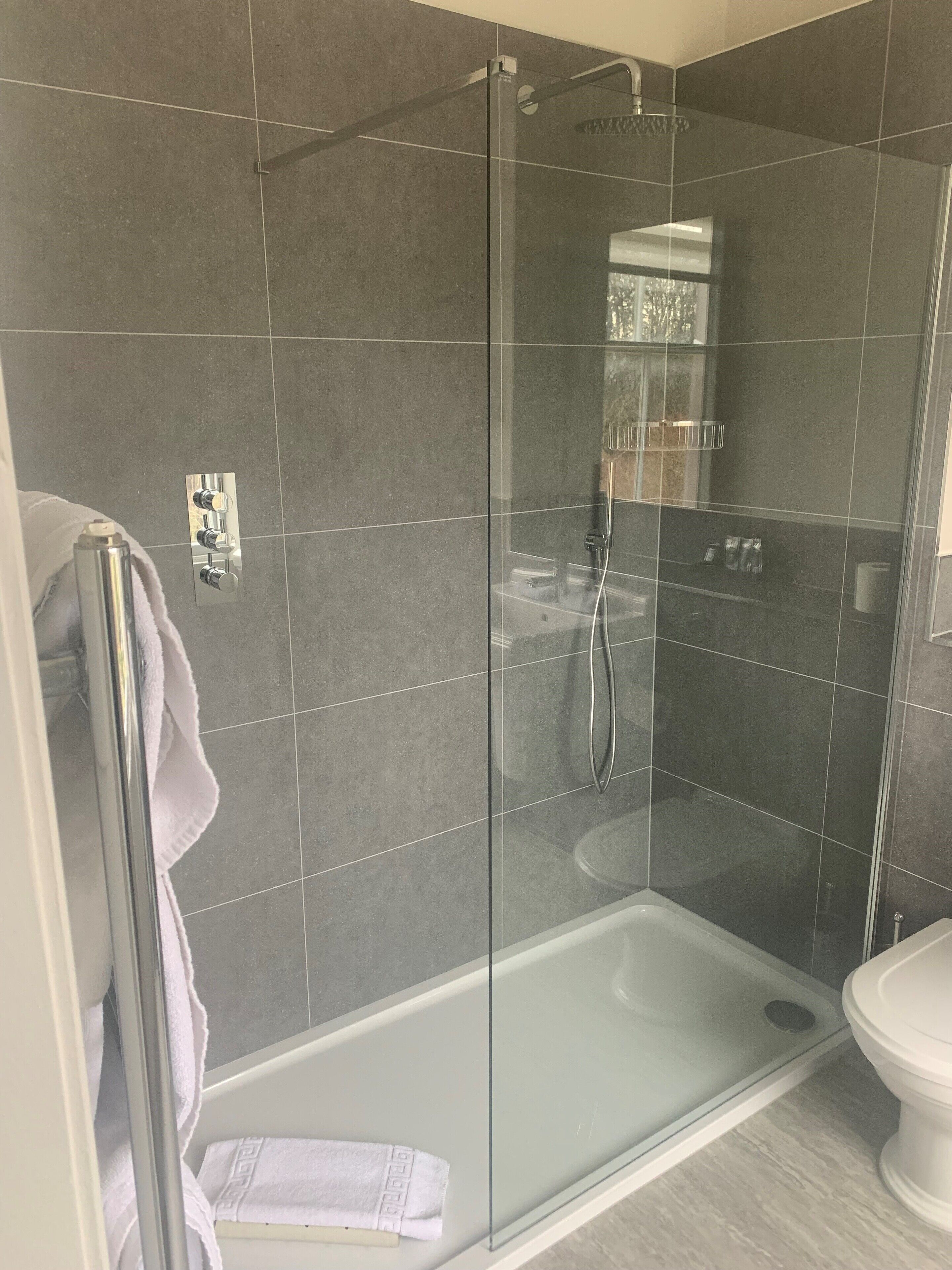 Ein modernes Badezimmer mit einer Duschkabine, einer weißen Badewanne und einem WC.
