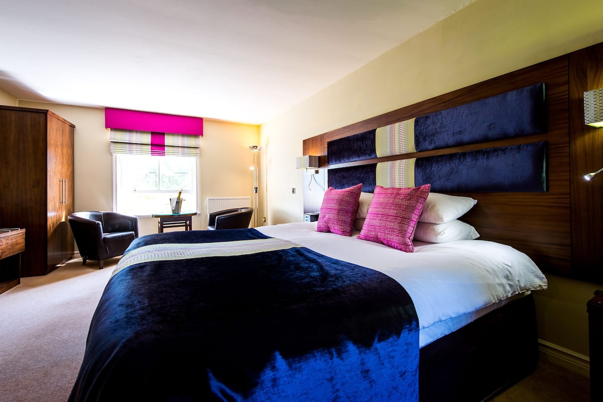 A hotel room with a large bed, a desk, and a chair.