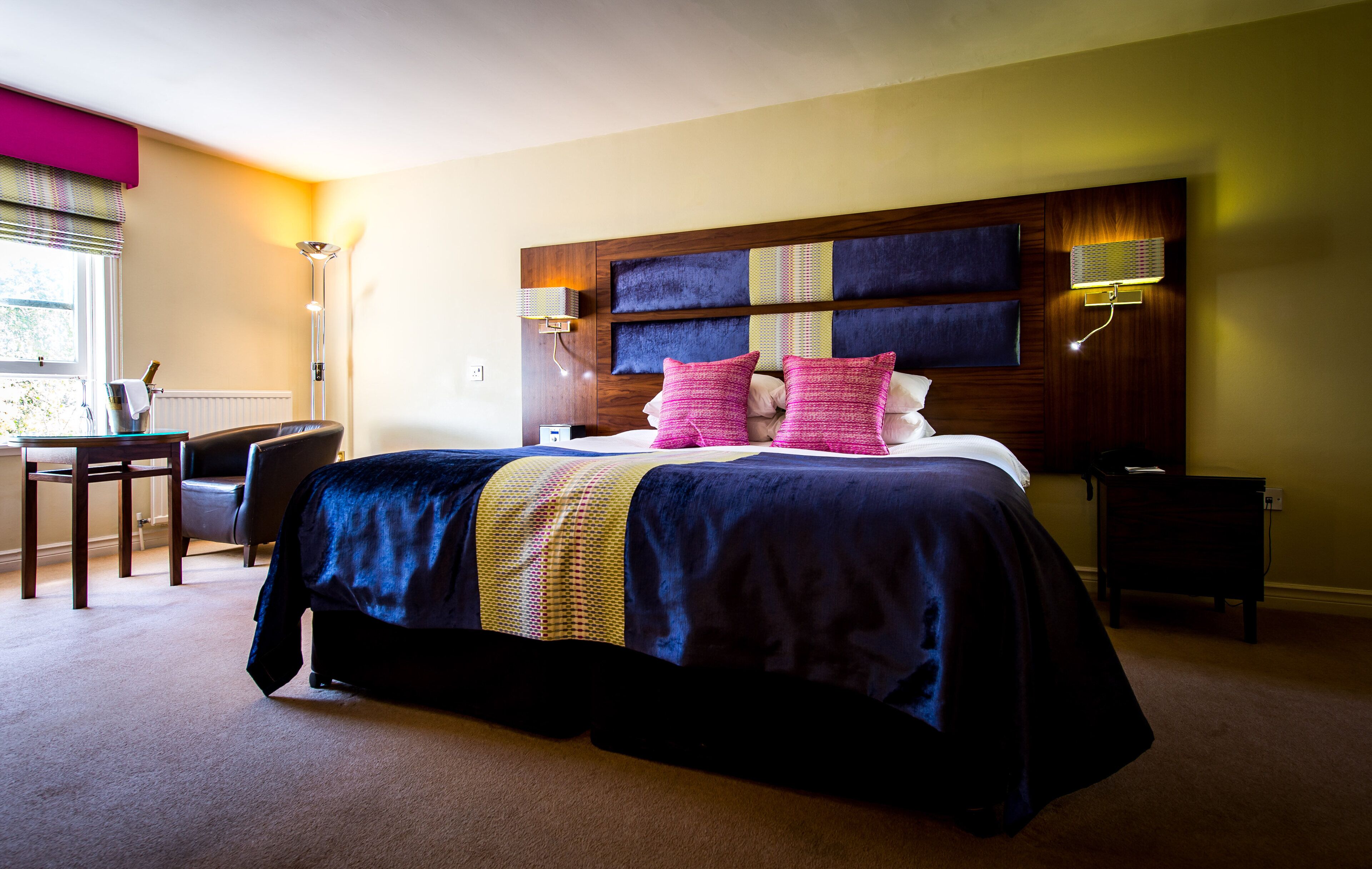 A hotel room with a large bed, a desk, and a chair.