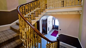 Un escalier orné de rampes dorées et surmonté d’un tapis à carreaux.