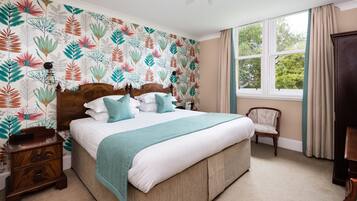 A bedroom with a large bed, a nightstand, a chair, and a window with curtains.