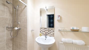 A bathroom with a shower, sink, mirror, and towel rack.
