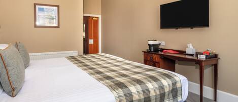 Una habitación de hotel con una cama, un escritorio, un televisor y una puerta.