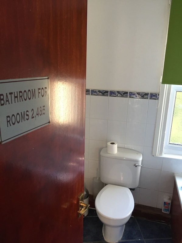 A bathroom with a sign indicating it is for rooms 2, 4, 5.