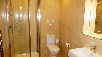 A bathroom with a glass-enclosed shower, a toilet, and a sink with a mirror above it.