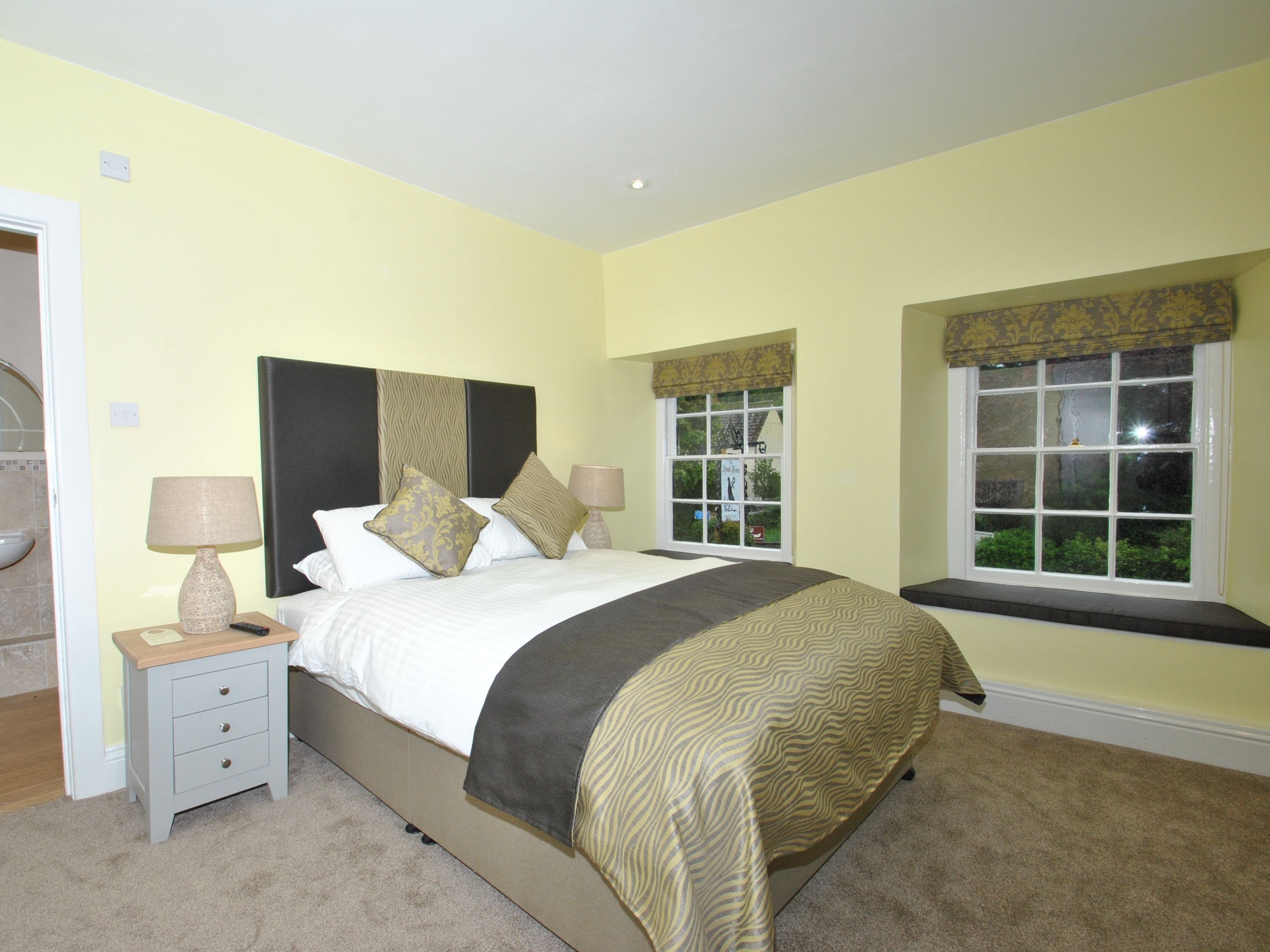 A neatly arranged bedroom with a bed, bedside tables, and a window with a view.