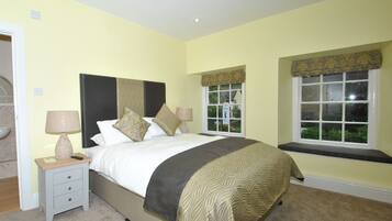 A neatly arranged bedroom with a bed, bedside tables, and a window with a view.