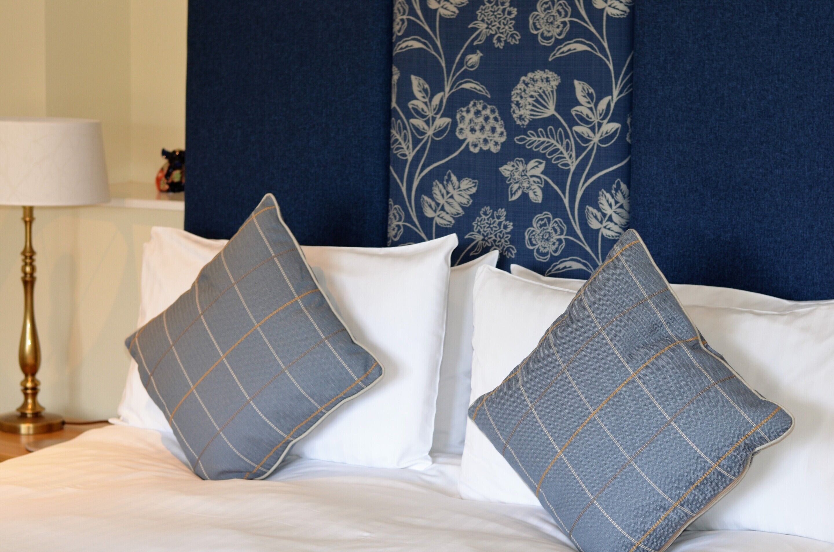 Una cama bien hecha con dos almohadas y un cabecero azul con estampado floral.