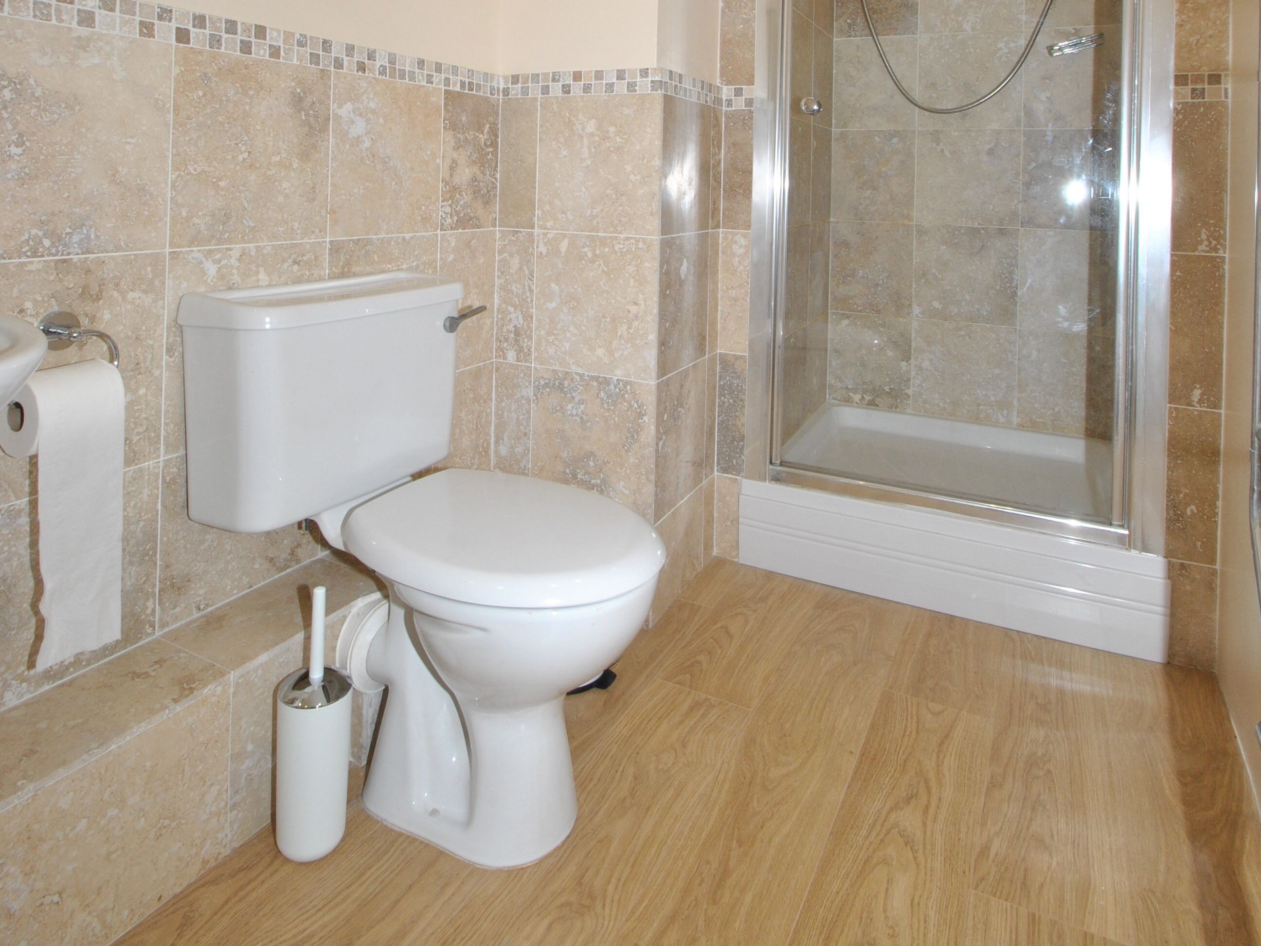 Une salle de bain équipée de toilettes, d’une douche et d’un porte-rouleau de papier toilette.