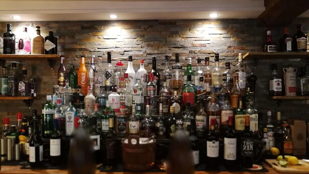 A bar area with a variety of liquor bottles and a wooden counter. - The Hood Arms (Bridgwater)