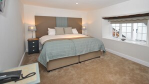 A bedroom with a bed, bedside tables, a window, and a carpeted floor. - The Hood Arms (Bridgwater)