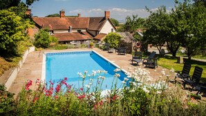 A rectangular swimming pool surrounded by a garden with various plants and flowers. - Castle of Comfort Hotel & Restaurant (Bridgwater)