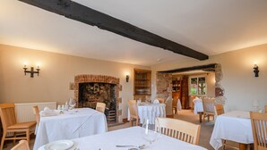 A dining area with multiple tables set for a meal, featuring white tablecloths and wooden chairs. - Castle of Comfort Hotel & Restaurant (Bridgwater)