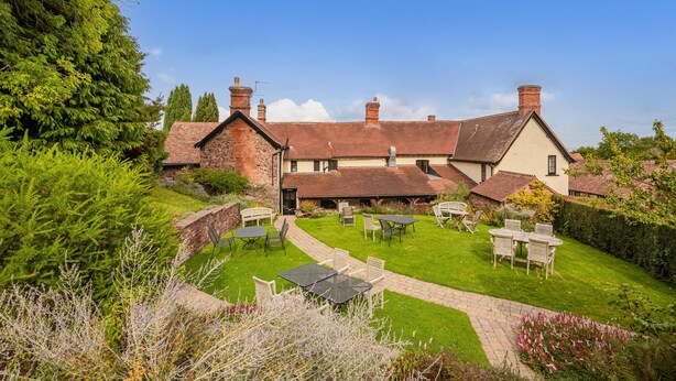A large, traditional building with a spacious courtyard, multiple chimneys, and a well-maintained lawn with outdoor seating. - Castle of Comfort Hotel & Restaurant (Bridgwater)