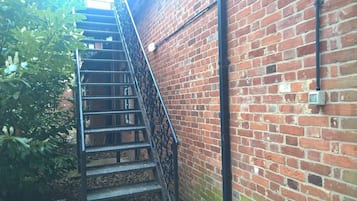Un edificio de ladrillo con una escalera metálica que sube a un nivel superior.