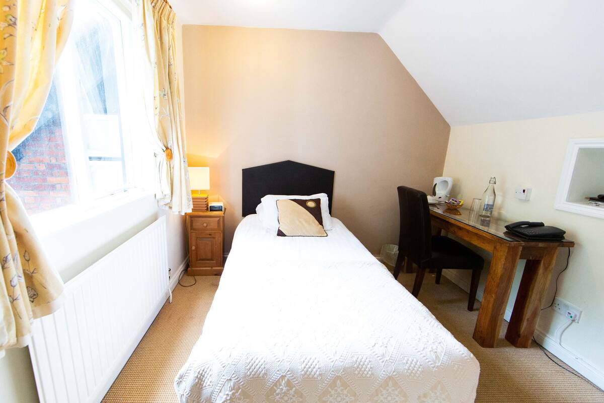 Een slaapkamer met een bed, een bureau en een stoel.