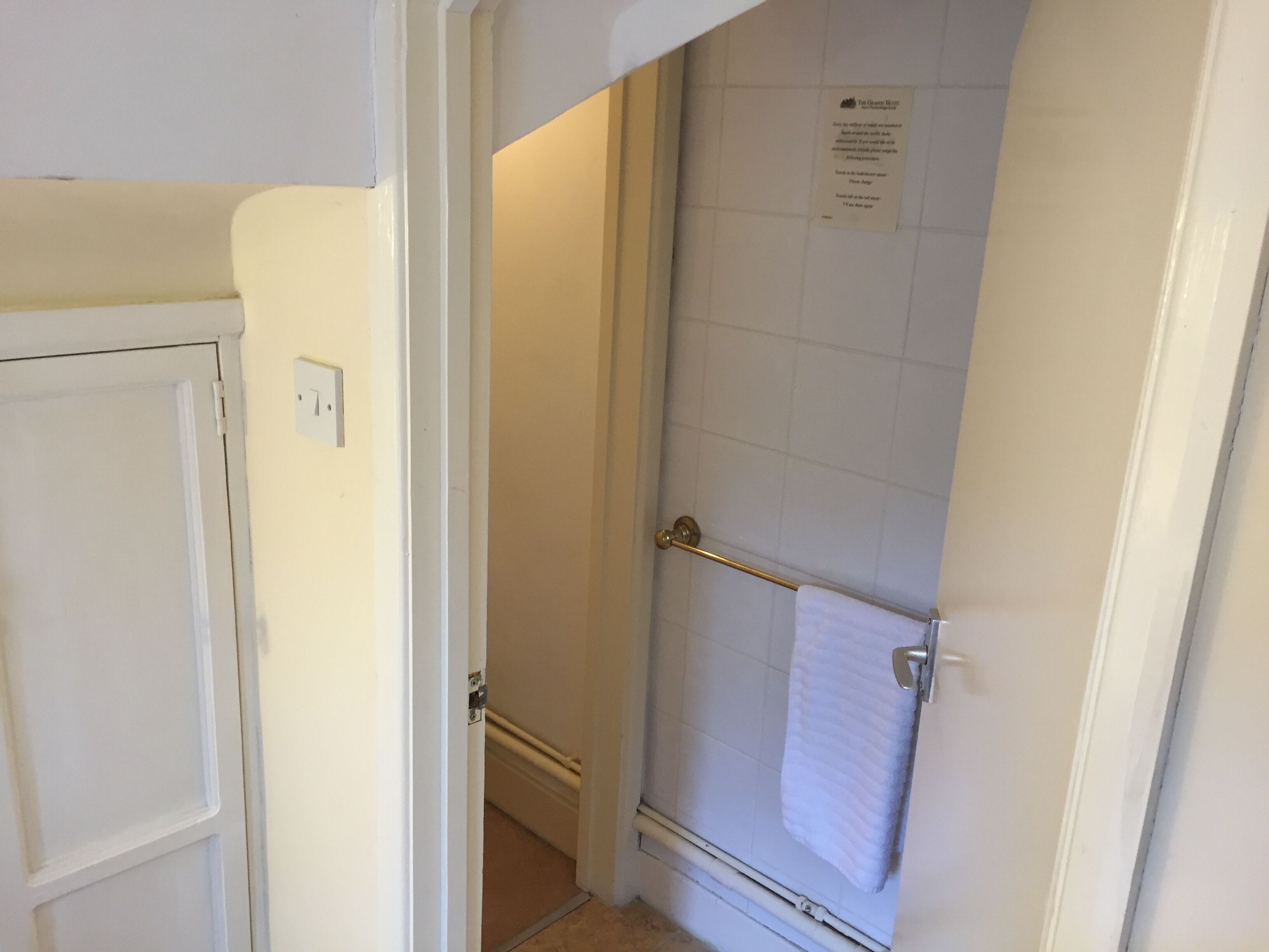 A bathroom with a white door, a towel rack with a white towel, and a sign on the wall.