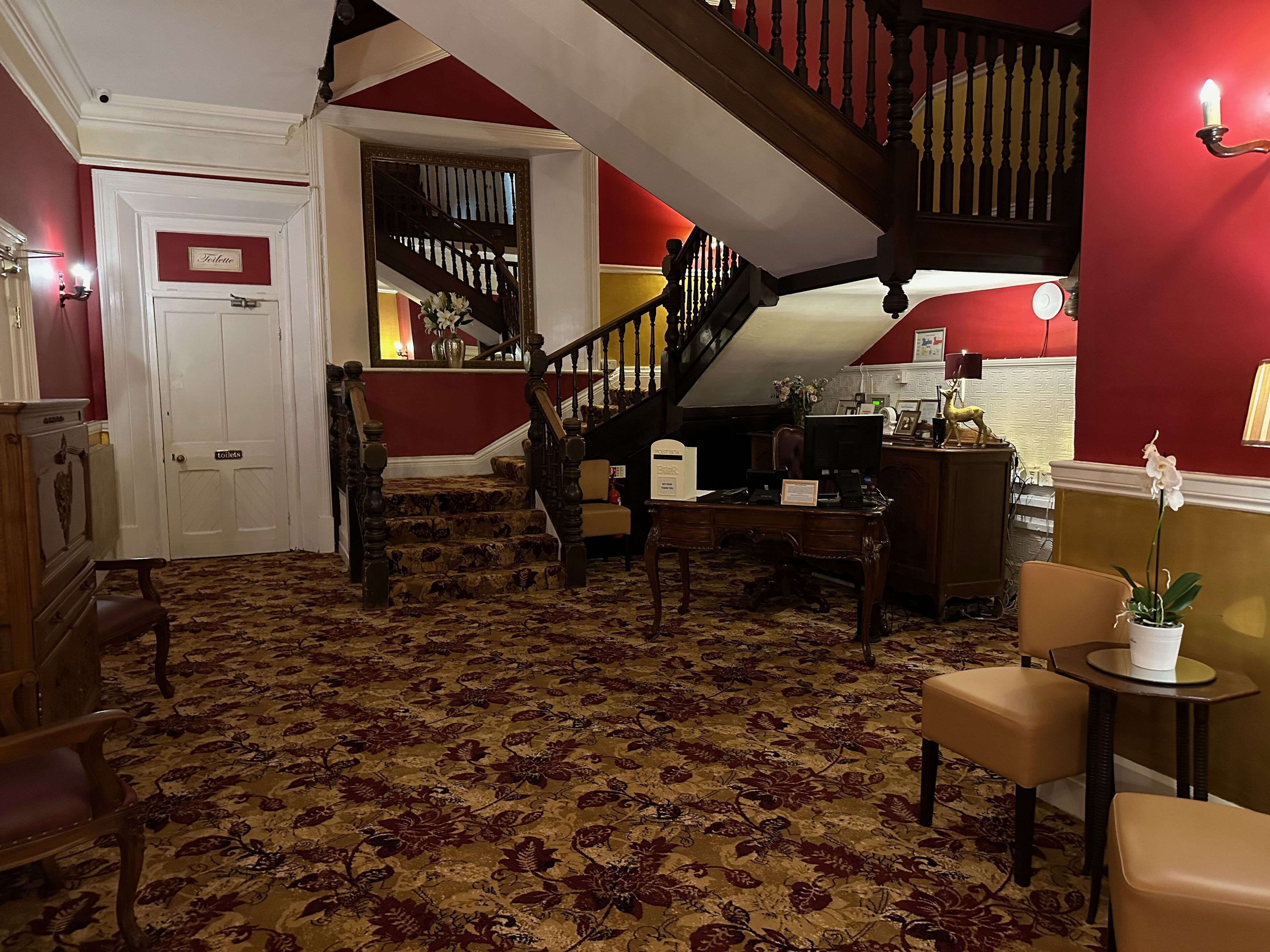 Un hall d’hôtel avec un escalier, un comptoir d’accueil et un espace salon.