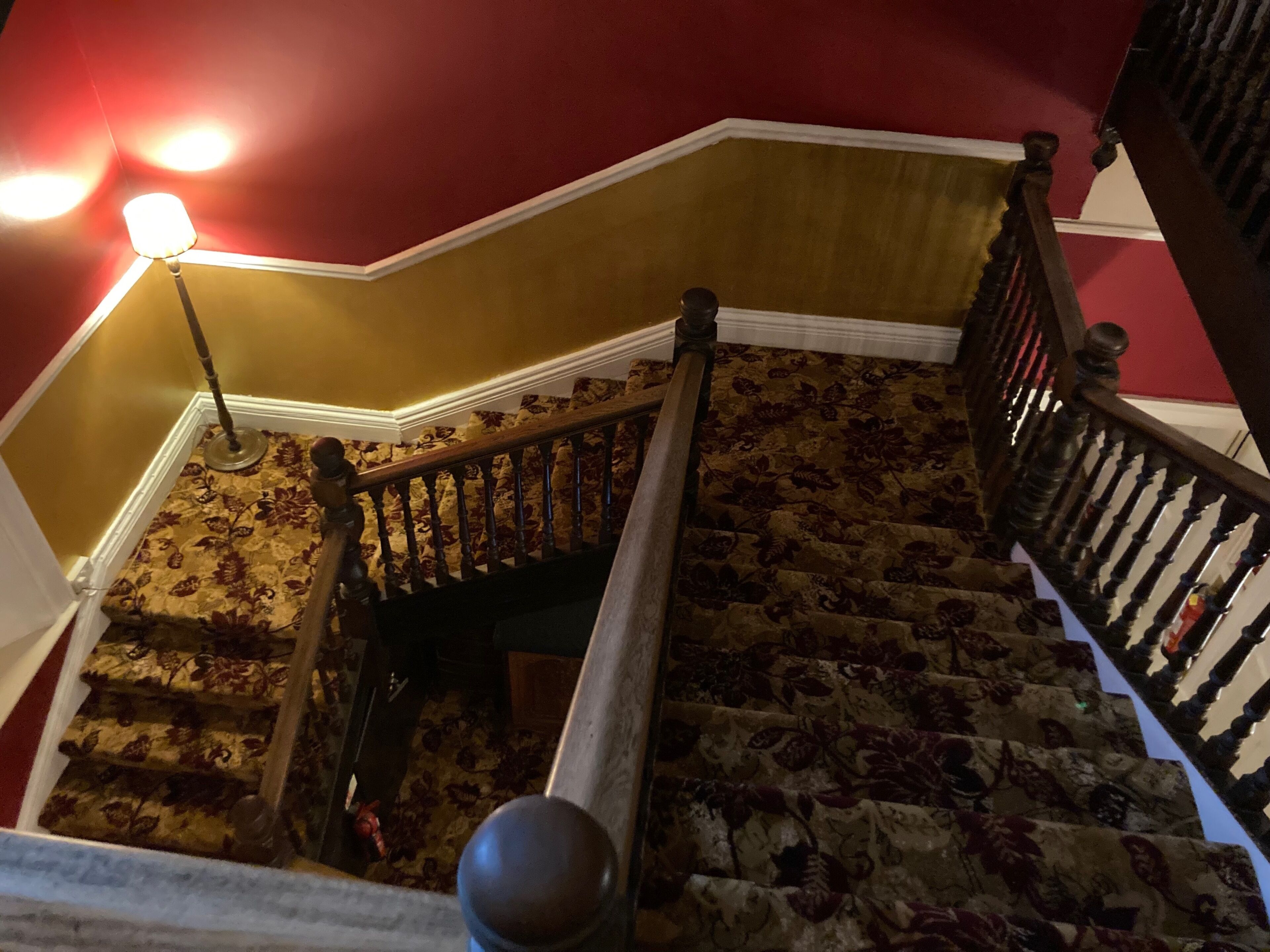 A staircase with a wooden handrail and a red wall.