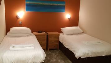 A room with two beds, a painting on the wall, and an air conditioner.