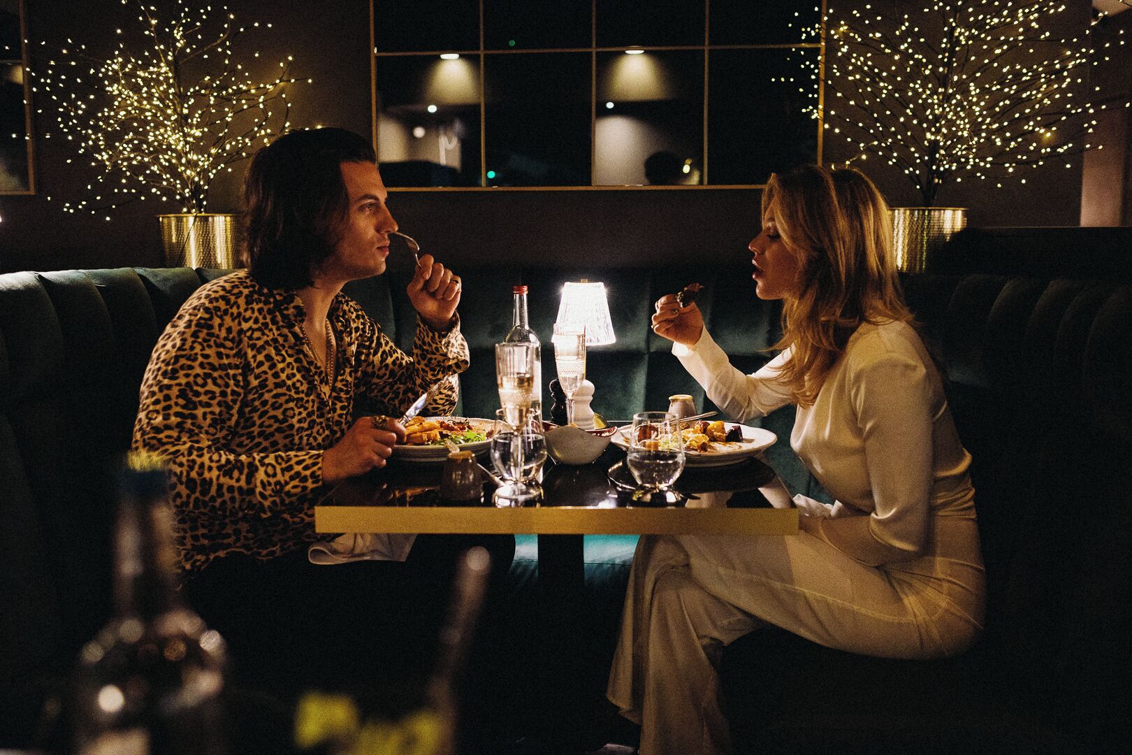 A dimly lit restaurant with two people dining at a table.