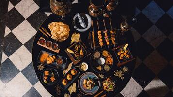 A round table with various dishes and drinks, surrounded by a checkered floor.