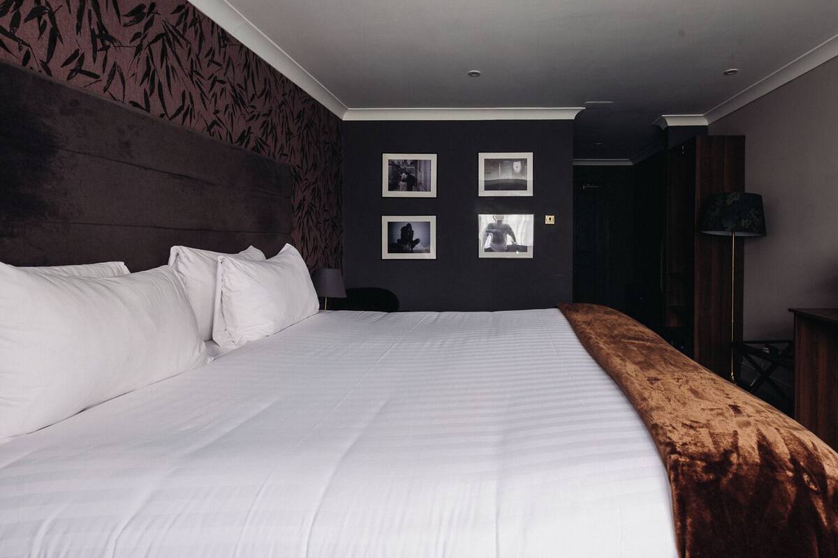 A neatly made bed with white linens in a hotel room.
