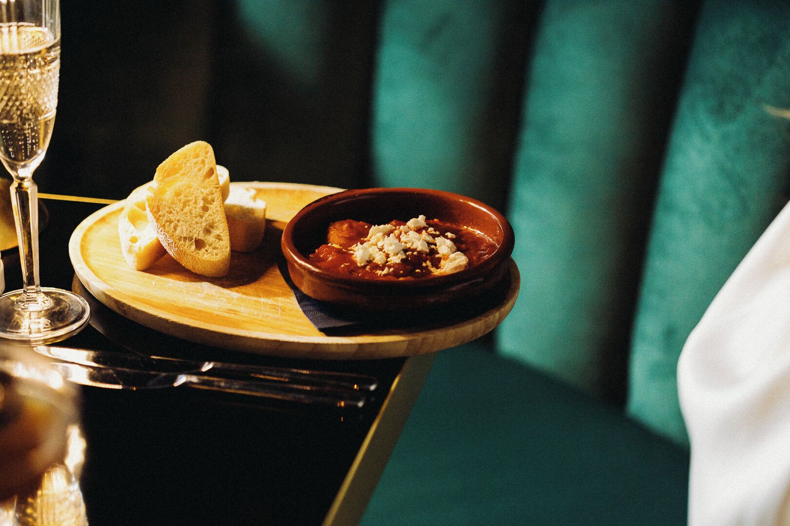 A dining table with a plate of food, a glass of wine, and a bowl of soup.